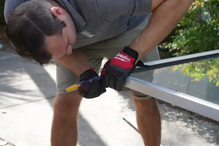 Stuck Door technician measuring a sliding glass door panel to confirm the standard sliding glass door size