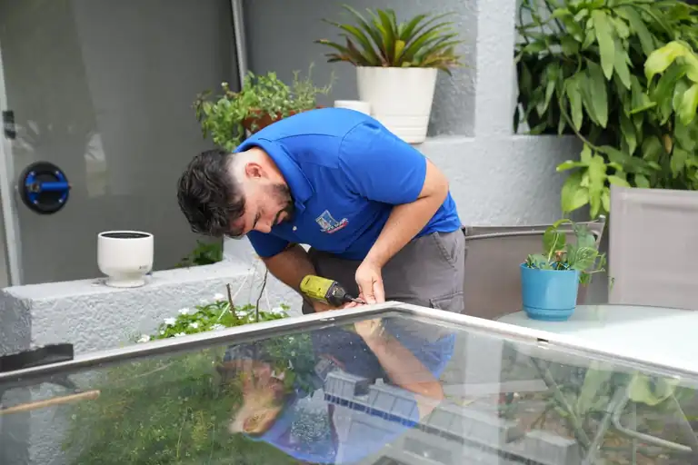 Technician replacing sliding glass door rollers on a removed patio door panel